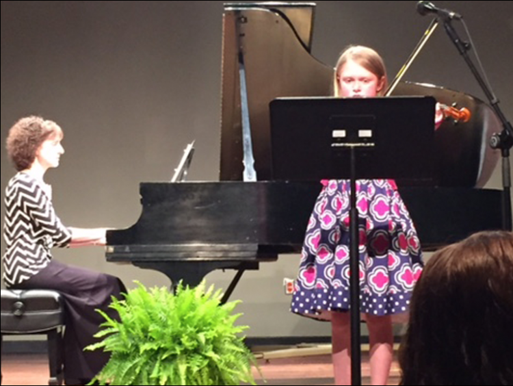 young girl playing violin on the stage