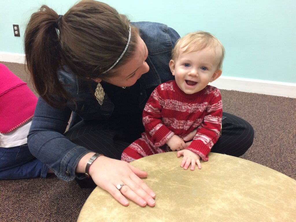 Picture shows baby playing a drum in Kindermusik class